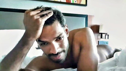 Handsome Indian man John Vesta lounging nude on bed in gay bukkake video