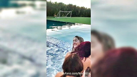 Blonde and purple-haired women embracing in infinity pool by soccer field