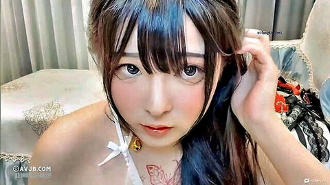 Cute Asian webcam girl in white lingerie with bow and bell showing cleavage and chest tattoo