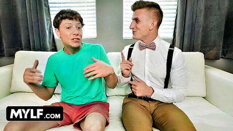 Curly-haired young man in green tee chats with suited older man on couch - MYLF