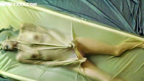Nude woman in tight vacbed, body visible through transparent latex