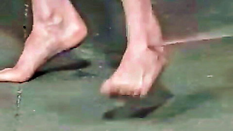 Close-up of wet bare female feet and legs splashing in water