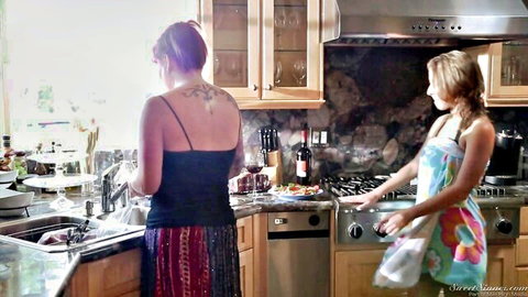 Presley Hart in colorful apron with tattooed brunette in kitchen