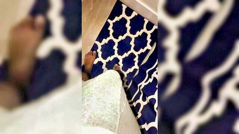 Blurry closeup of bare foot on rug with white lacy skirt, teasing pose