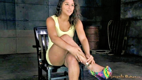 Abella Danger in yellow tank top and shorts, legs crossed in heels