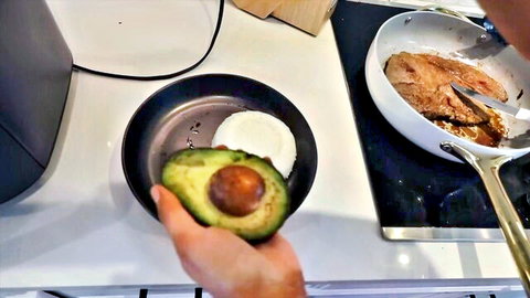 Hand preparing muscle-building meal: avocado on rice with grilled steak