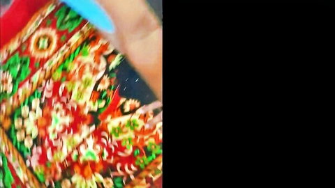 Close-up of vibrant colorful floral bedspread with turquoise finger on edge