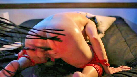Bound MILF arched in red ropes, exposed for spanking and anal play