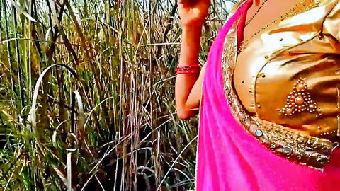 Seductive Indian bhabhi in pink saree posing in jungle field outdoor