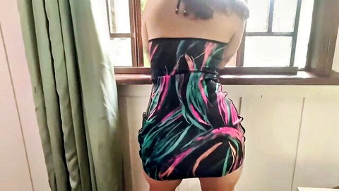 Purple-haired babe with big juicy ass in tight colorful mini dress standing by window teasing rear view