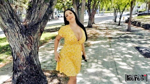 Angela White in sexy yellow floral dress, deep cleavage pose outdoors