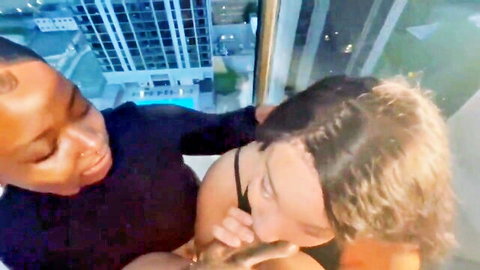 Black stud gropes white babe's tits on high-rise balcony at night