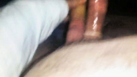 Blurry gloryhole scene with woman's oiled legs and ass visible through wall