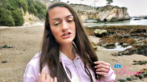 Summer Renee, hot brunette in pink hoodie, posing on scenic beach