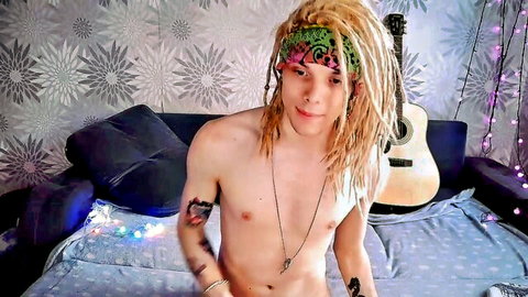 Slim blonde dreadlocked twink posing nude with guitar