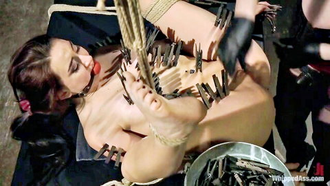 Bound brunette endures clothespin torture by blonde dominatrix in dungeon
