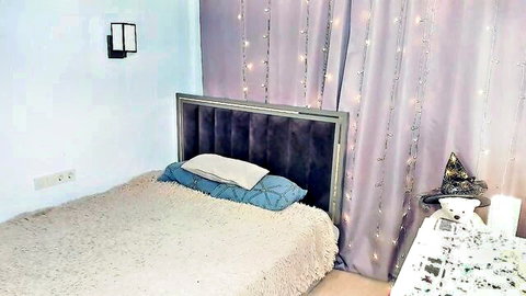 Cozy empty bedroom with purple fairy light curtains and plush bed ready for babe solo play