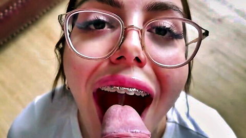Braces Asian teen with glasses sticks tongue out licking hard cock closeup