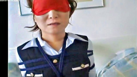 Blindfolded Asian woman in tight navy rope bondage vest over white shirt