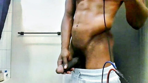 Muscular black man gripping erect cock in pulled-down shorts