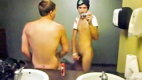 Two nude gay guys in bathroom selfie, one with hard cock exposed, other showing bare ass