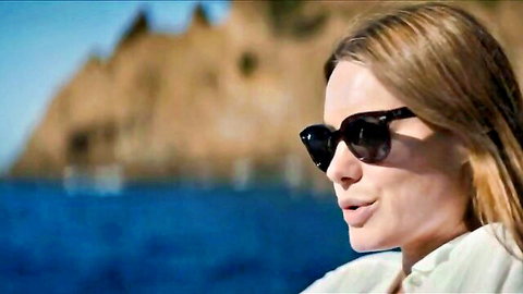 Camille Rowe in sunglasses on boat, teasing lips in sexy movie scene