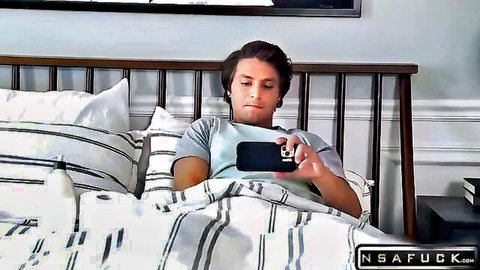 Young man lounging on bed, scrolling phone in step-sister tease scene