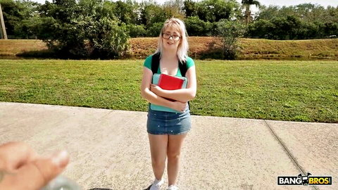 Nerdy blonde schoolgirl in short skirt holding books outdoors
