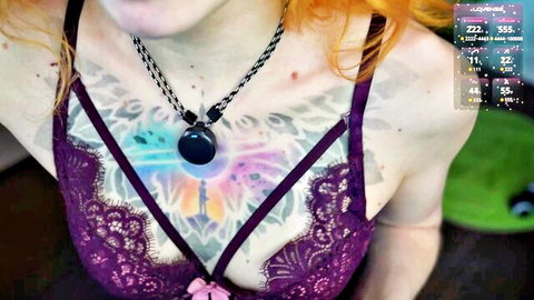 Juicyshow redhead model in purple lace bra, showcasing chest tattoos and deep cleavage