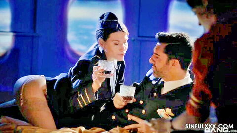 Brunette flight attendant in uniform skirt hiked up exposing ass toasts drink with pilot on bed