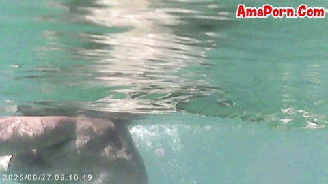 Nude woman posing underwater in pool, teasing view of ass and legs