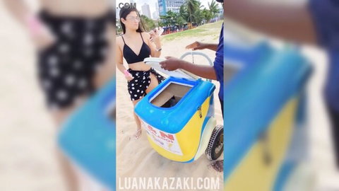 Luana Kazaki in black bikini and skirt at beach with ice cream seller