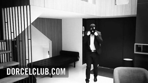 Mysterious masked man in black suit stands in modern luxury loft ready for intense action
