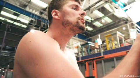 Muscular shirtless hunk with beard in industrial warehouse setting