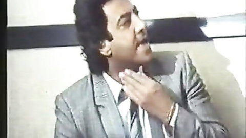 Vintage suited man smirking seductively in 1987 Italian porn scene
