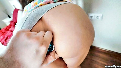 Melanie Queen bent over with panties pulled aside for butt plug insertion