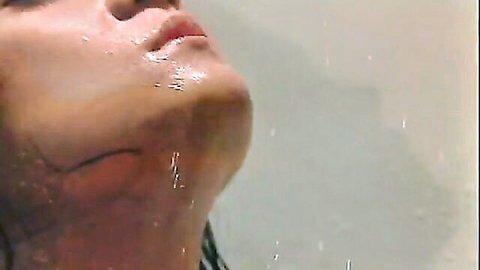 Aroused Asian woman in shower, water streaming down face and neck in ecstasy