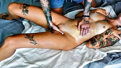 Tanned tattooed woman getting intimate oil massage, nude and aroused