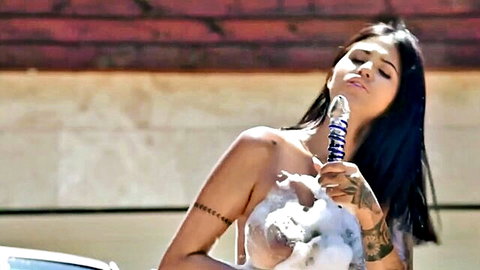 Tattooed brunette sucking blue swirled dildo with soapy big tits exposed outdoors