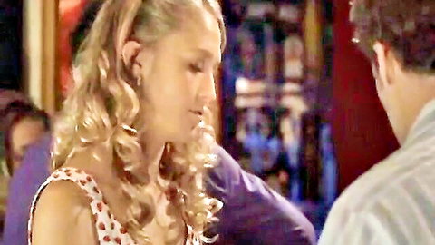 Blonde curly-haired woman in polka-dot dress talking intimately with man