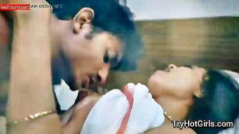 Man passionately kissing young South Asian woman's lips in bed with white sheet covering her tits