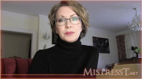 Brunette MILF mistress in glasses and black turtleneck sweater gazes seductively
