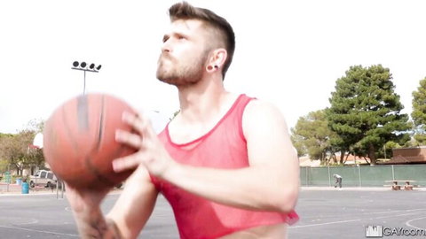 Sweaty muscular bearded man in red mesh tank top holding basketball on court