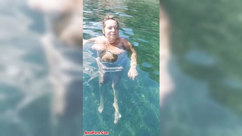 Mature woman nude floating in crystal clear turquoise waters