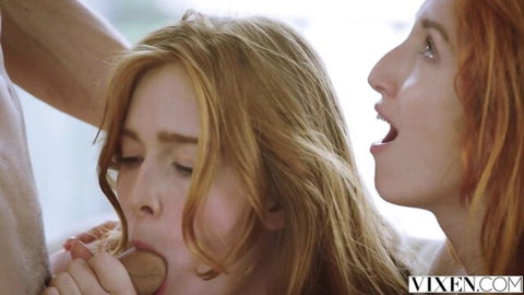 Redhead babe sucking thick cock deeply while another redhead watches with open mouth