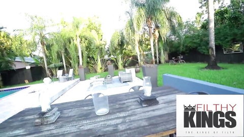Luxurious outdoor poolside with palm trees and Filthy Kings watermark awaiting hot filthy sex