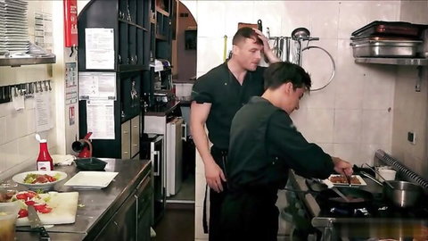 Two muscular Asian chefs in uniforms cooking in kitchen