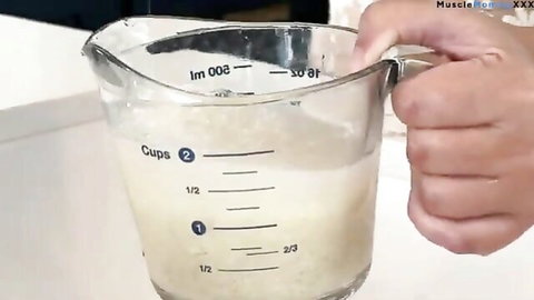 Hand measuring yellowish liquid in cup for low-carb high-protein recipe