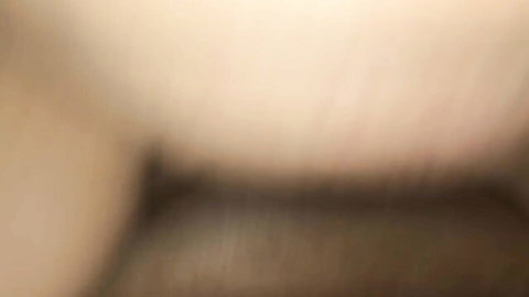 Blurry POV close-up of smiling blonde in white tank top showing cleavage