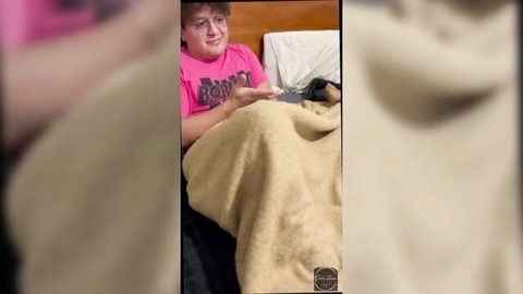 Curly-haired stepsister in pink shirt comforts on bed after breakup